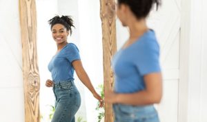 happy woman looking in mirror happy with her weight loss results